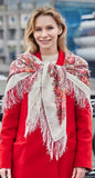 An elegant winter lifestyle shot showing a woman draped in an oversized ivory wool scarf with pink and orange roses.