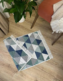 Geometric patterned rug on a wooden floor with a plant and chair in the background