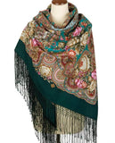 Colorful rose-patterned woolen scarf with fringes on a deep green base on a mannequin against a white background.