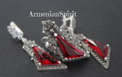 This sterling silver jewelry set, featuring large red stones, is an eye-catching statement piece. The rich, deep hue of the stones is beautifully contrasted by the cool gleam of the silver and the subtle sparkle of the marcasites. The delicate bow details add a touch of femininity and vintage charm, preventing the pieces from feeling too heavy or overpowering despite their size. The earrings are substantial yet comfortable to wear, and the ring makes a bold impact on the finger. 