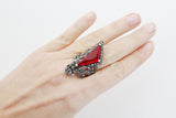 This ring is not for the faint of heart – it’s a statement piece that demands attention! The large, ruby red stone is the clear focal point, boasting a deep, rich color that evokes images of royalty and old-world glamour. The stone is not subtle; it's bold and captivating, catching the light beautifully.

