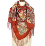 Red floral and paisley patterned Slavic scarf with fringes on a mannequin against a white background