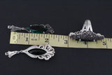 Extra long earrings with marcasite and green stone near a ruler showing 2 inch length.