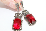 Long Tudor-style dangle earrings in 925 sterling silver with a large central red stone surrounded by intricate marcasite settings, handcrafted by the Armenian Spirit brand.