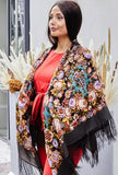 A woman wearing a beautifully crafted chocolate brown pashmina shawl made from authentic merino wool. The beige and navy blue ornaments and flowers create a refined contrast, complemented by an elegant silky fringe.