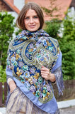 Woman wearing a large, colorful floral-patterned shawl outdoors.