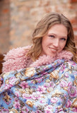 Woman wearing a floral-patterned light blue shawl with a brick wall background