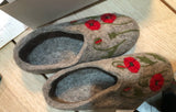 Pair of merino wool shoes-slippers with floral design on a wooden surface