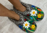 Gray slippers with floral designs on a light wooden floor