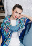 Woman wearing a blue floral woolen scarf with tassels with delicate pink and sky blue flowers in vintage style.