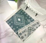 Geometric patterned rug on a marble floor with a chair and plant in the background.