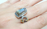 Rectangular ring featuring labradorite gemstone with gold-plated accents and a ring attached to the top. The ring has a round and geometric other details on a hand with the text 'ArmenianSpirit' visible.