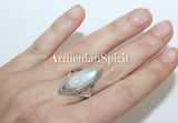 A sterling silver 925 ring with a large moonstone and labradorite set on a hand, with gold plated accents.