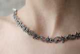 Necklace collar with small black flowers and marcasite on a woman`s neck.