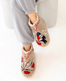 Pair of decorative bootie slippers made of natural sheep wool with a bird design on a white background