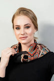Woman wearing a patterned black, red and turquoise woolen scarf on a plain background