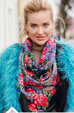 Woman wearing a colorful floral scarf with a blue fur coat. The scarf is black with red Slavic style vintage roses, It is made of high quality merino wool and silky fringe.
