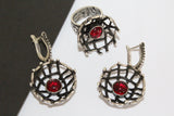 A set of sterling silver jewelry including oxidized black net design earrings and a matching ring, each adorned with a red garnet stone.