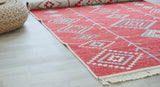 Red patterned rug on a light wooden floor with a woven basket.