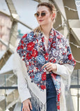 A detailed shot of a luxurious Slavic-style merino wool palantine. The oversized scarf displays a rich botanical border design filled with blooming red roses and complex gray-blue floral scrollwork, finished with a highly textured, flowing white fringe at the bottom hem.