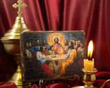 Traditional Orthodox Last Supper icon handcrafted on solid pine wood in old style with a bright candle in frond and red sulky fabric under.