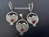 Silver jewelry set with pomegranate design and red gemstones on a black background with Ararat mountain and grape ornaments in Armenian style.