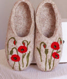 A pair of beige felted wool slip-on slippers decorated with red poppy flowers and green stems, shown against a neutral background.
