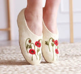White slippers with red floral embroidery on a light background
