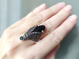 A pair of silver earrings featuring black onyx and marcasite, held in a person's hand.