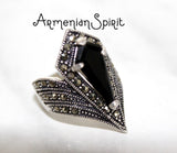 A black stone ring with marcasite accents on a sterling silver 925 band, displayed on a person's hand.