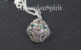 A sterling silver pendant with a rainbow topaz centerpiece, flanked by two smaller marcasite stones, accompanied by a silver chain.