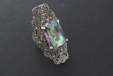 Large rectangle ring with marcasite and green mystic topaz with purple hint made from sterling silver on a black surface.
