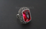 Ring with a red gemstone and silver detailing on a dark background