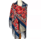 A high-quality woolen scarf with a deep blue base and a striking vintage pattern of large red peony flowers with green leaves. The scarf is styled on a professional mannequin against a clean white background, highlighting its rich fabric folds and matching blue fringe trim.