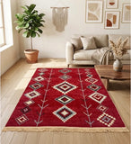 A red area rug with a geometric Southwestern-style diamond pattern in beige, blue, and white, styled on a light wood floor in a modern living room setting.