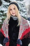 Woman wearing a decorative woolen red scarf with fringe in a snowy outdoor setting