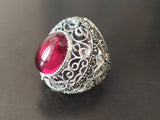 A dome ring with red jewelry stone set in a silver mounting with intricate designs with marcasite and filigree