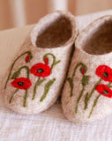 Pair of felted slippers with red embroidered poppy flower designs on a light background