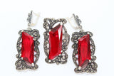 A set of sterling silver jewelry featuring very long earrings and a finger cover ring, adorned with sparkling marcasite and red topaz.