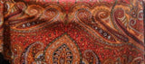 Close-up of a red and orange paisley patterned shawl.
