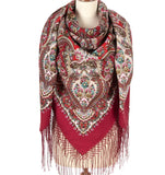 Red patterned woolen scarf with silky fringes on a mannequin against a white background