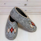 Merino wool slippers in gray with red and beige rhombus design embroidery on a wooden background.