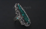 Decorative ring with green gemstone and silver detailing on a black background
