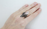 A white stone ring with marcasite and small black stone on a woman hand