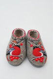 House shoes made of sheep wool with red bird and berries embroidery on a white surface.