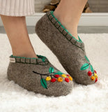 Gray merino wool slippers with floral design on a white carpet