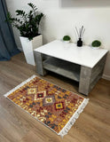 Decorative Armenian rug with geometric traditional pattern on a wooden floor, table with plants in the background