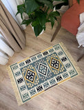 Decorative Armenian rug with geometric pattern on a wooden floor, next to a plant and chair.