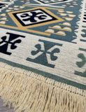 Close-up of a patterned rug with geometric designs and fringes.