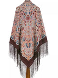 Patterned shawl with fringes on a white background Made from natural merino wool, this brown Slavic-style shawl is soft and warm. A woman wearing it can wrap it comfortably, with light blue and red details and a smooth, silky fringe.